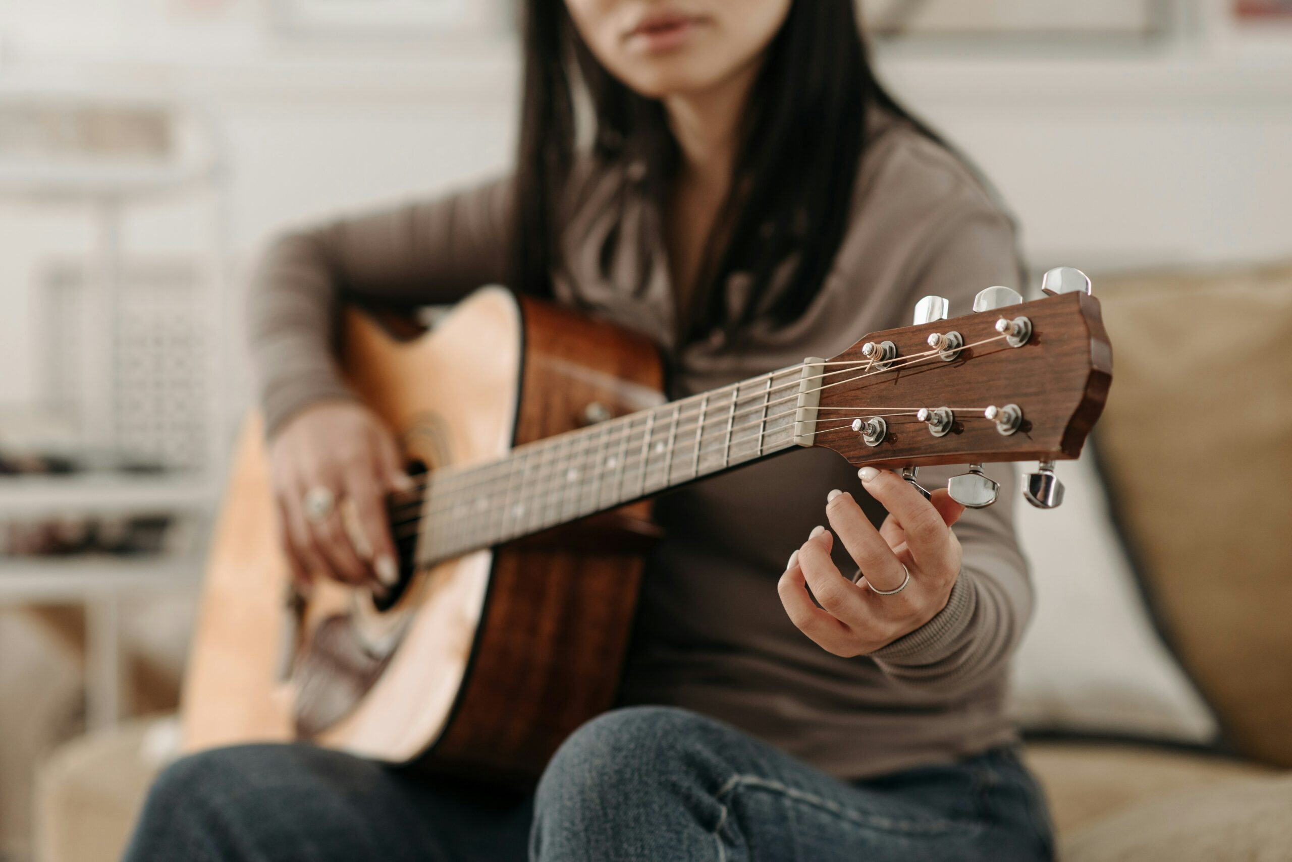 Young woman tuning acoustic guitar