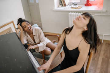 Two girls having fun playing the piano