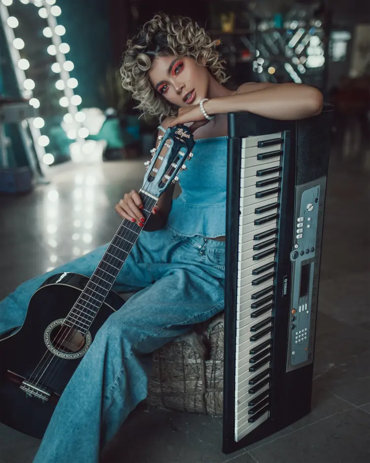 A woman posing with a keyboard and a guitar.