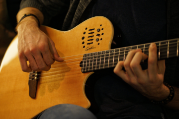 A close up of a musician playing a guitar.