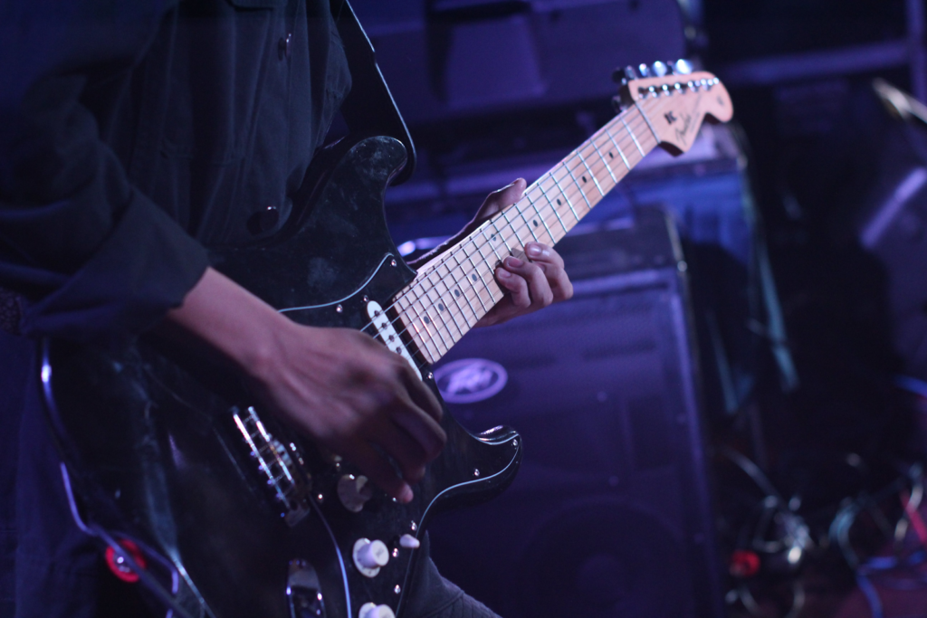 A close up of a man playing electric guitar on stage.