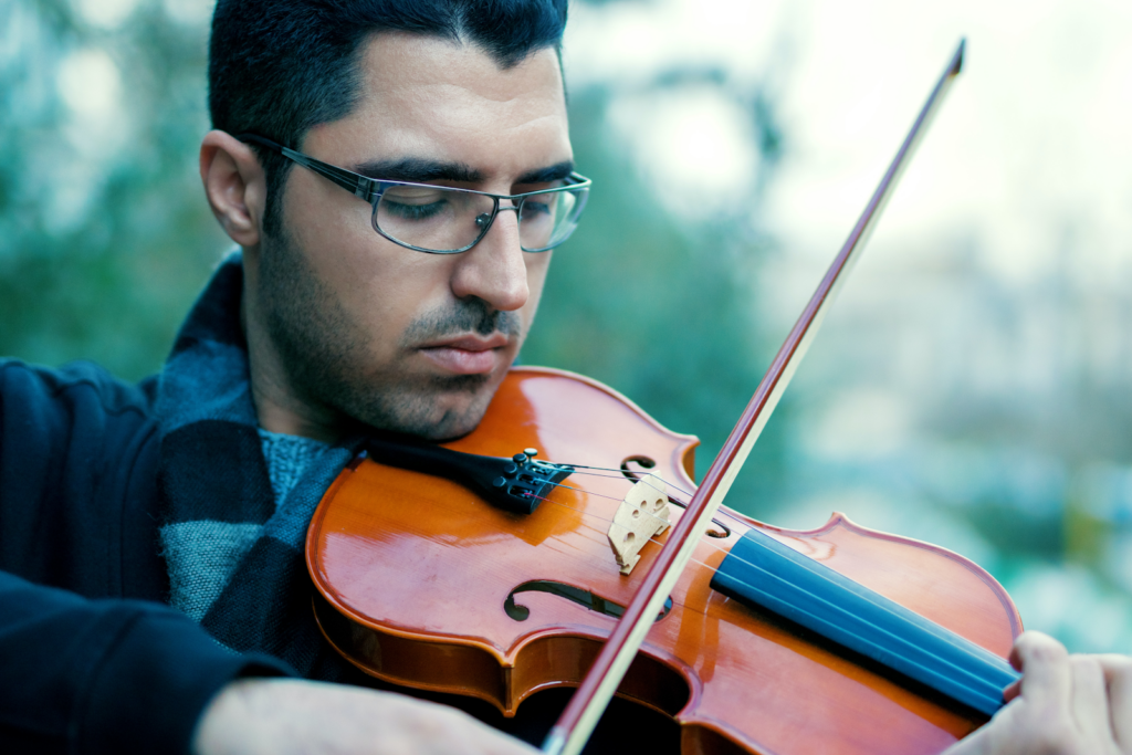 A close up of a man wearing glasses playing violin
