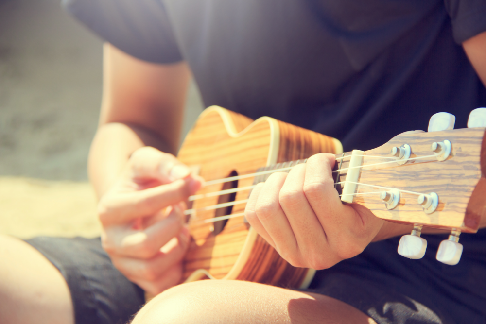 A close up of a musician playing a ukulele.