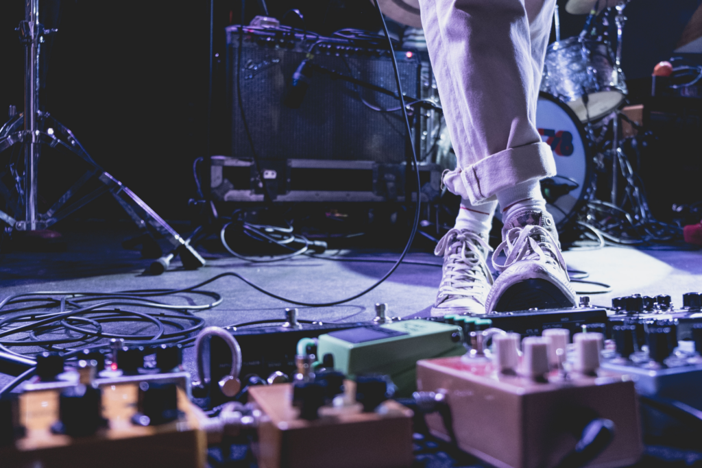 A performer using various guitar pedals on stage.