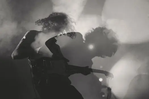 A guitarist performing on stage with smoke and lights.