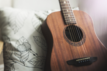 An acoustic guitar on a printed bedsheet.