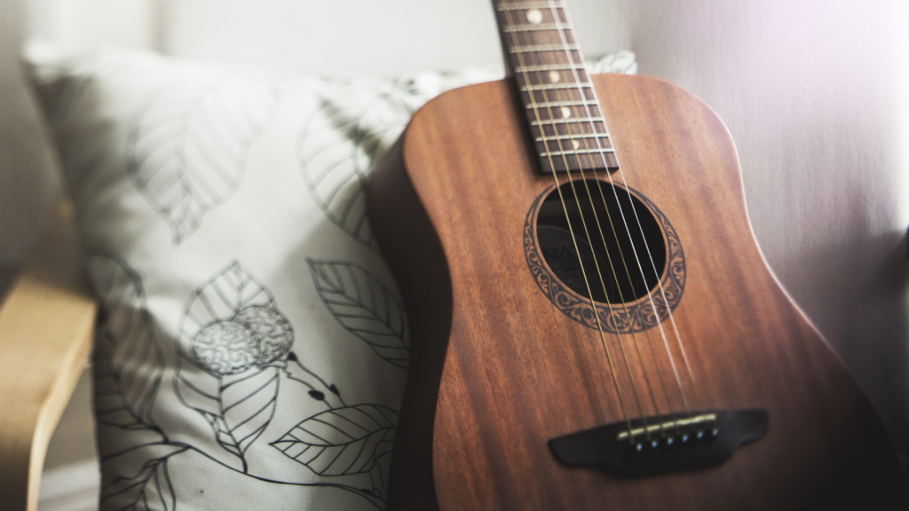 An acoustic guitar on a printed bedsheet.