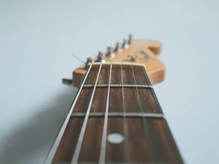 An extreme close up of the neck and strings of a guitar.