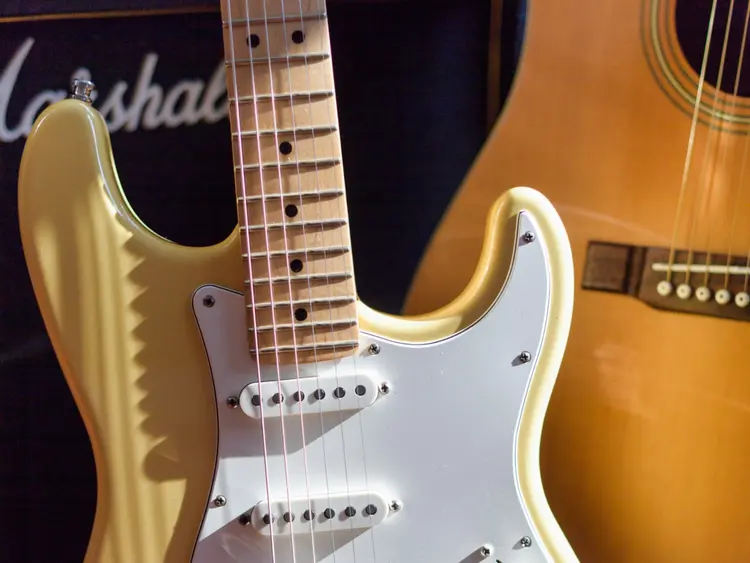A closeup of an electric guitar with a Marshall amp in the background.