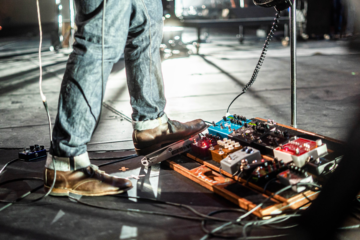 A close up of a musician using various guitar pedals.