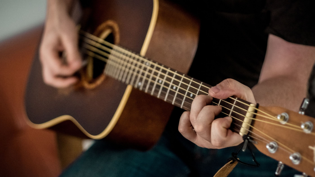  a close up of a man playing an acoustic guitar.