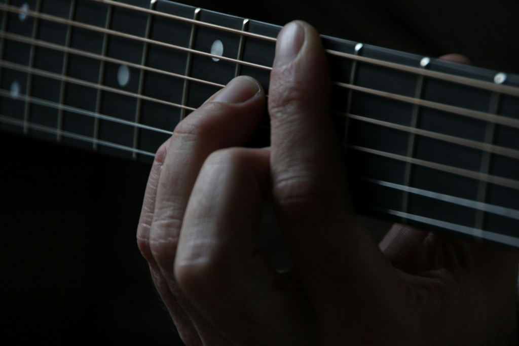 Close up of a guitarist playing a chord.