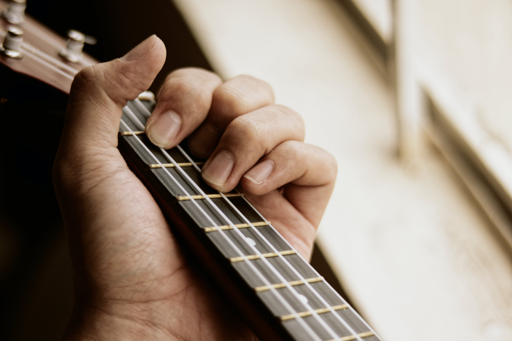A persons' hand on a guitar neck.