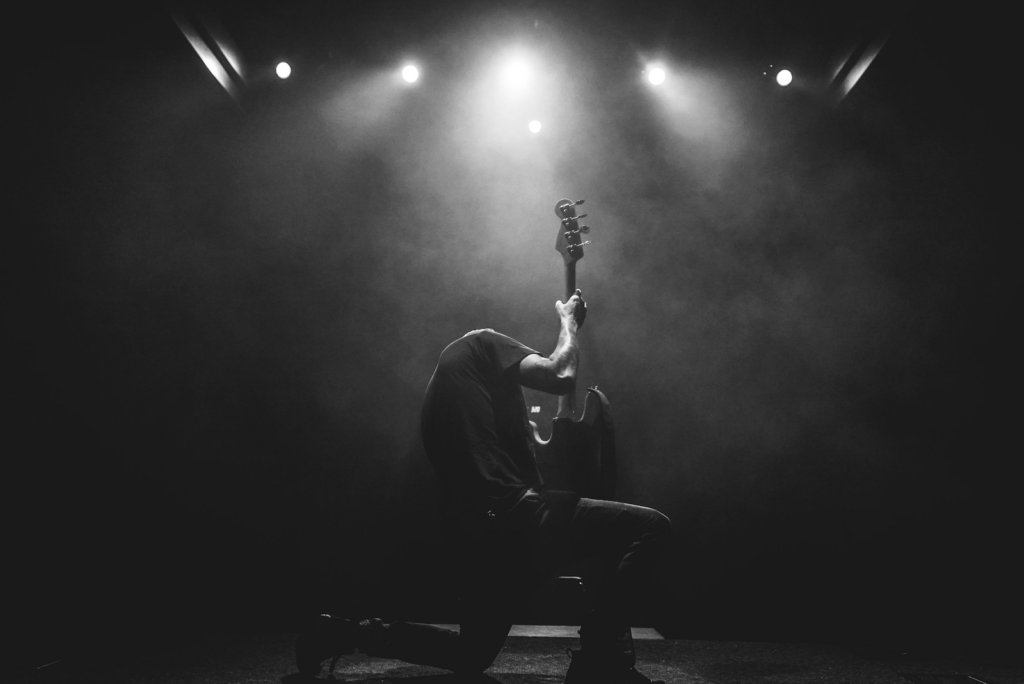 a black and white image of a guitarist performing on stage.