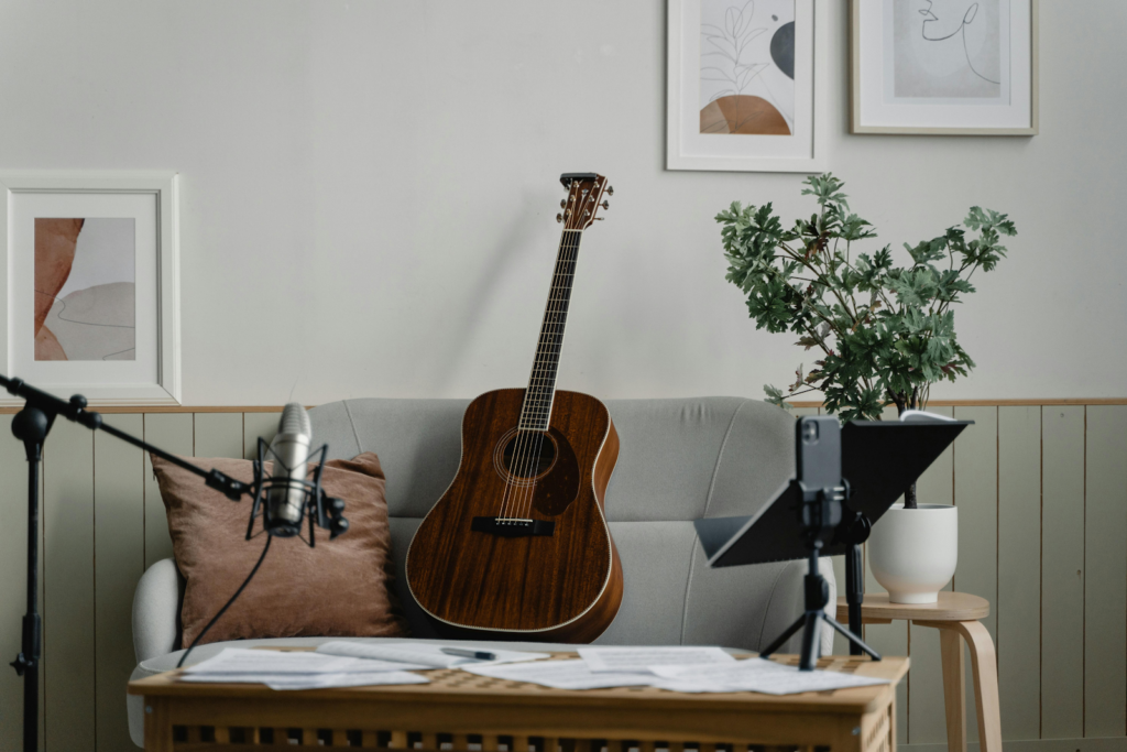 An acoustic guitar on a couch with a recording mic.