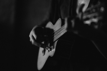 A black and white image of a man playing a guitar.