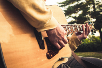 A close up of a man playing a guitar.