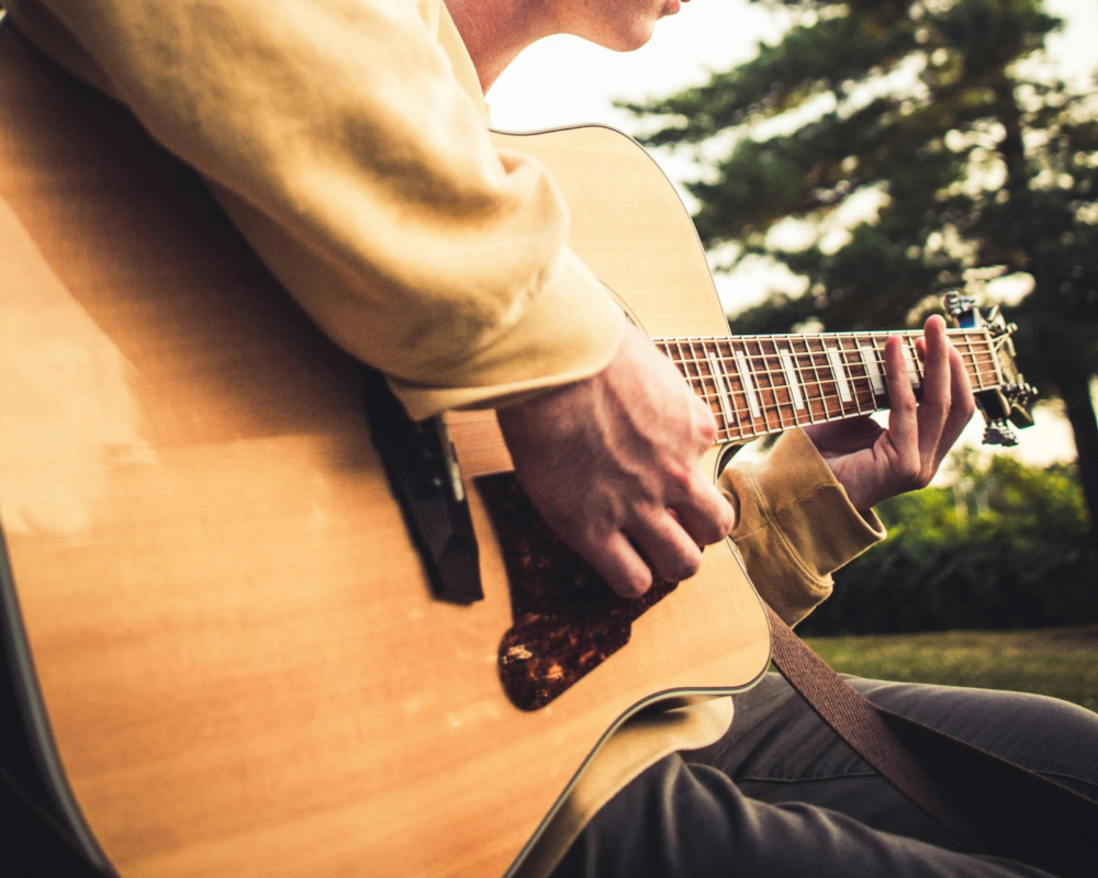 A close up of a man playing a guitar.