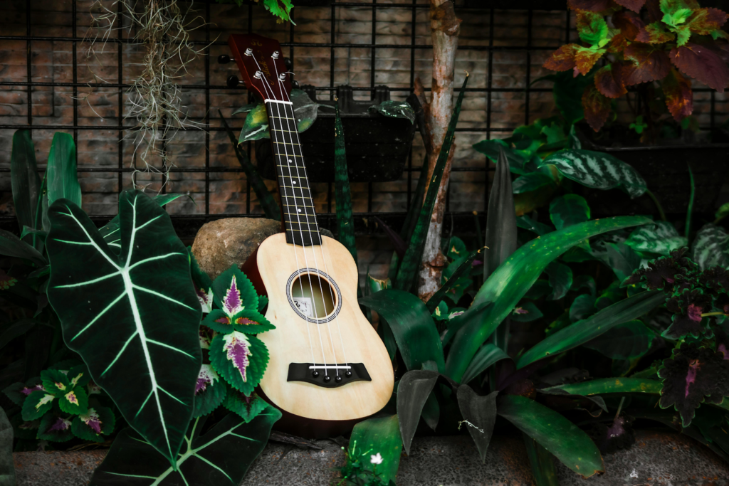 An acoustic guitar standing upright in a garden.