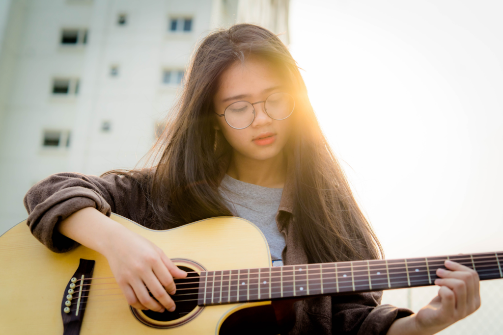 A young girl playing an acoustic guitar.