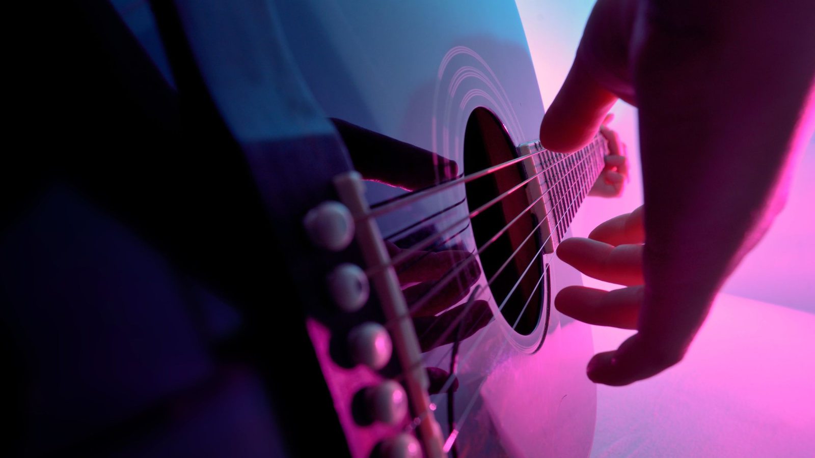 An artistic shot of an acoustic guitar being strummed.