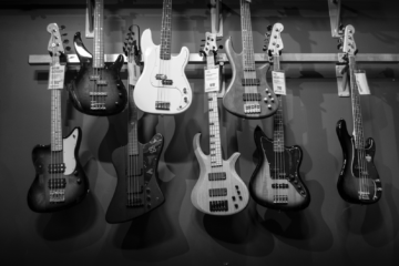 A black and white image of electric guitars being displayed on the wall of a guitar store.