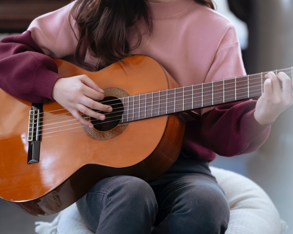 a girl strumming an acoustic guitar.