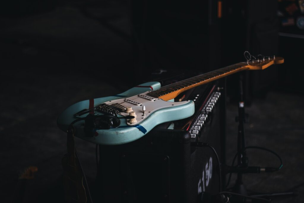 A white electric guitar lying on top of an amp.