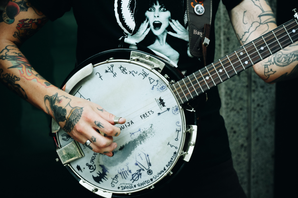 A heavily tattooed man playing a banjo.