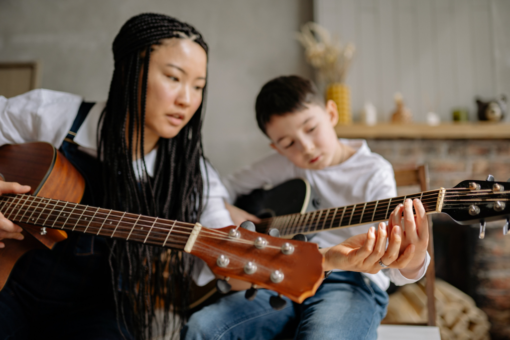 A guitar teacher teaching a young student how to play.