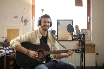 A guitarist in a home studio with a mic, and headphones.