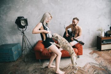 A man playing guitar, while a woman and her dog play.