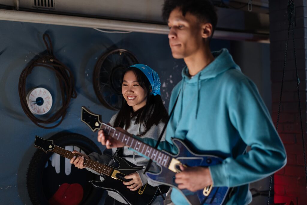 A young woman and man playing electric guitars.