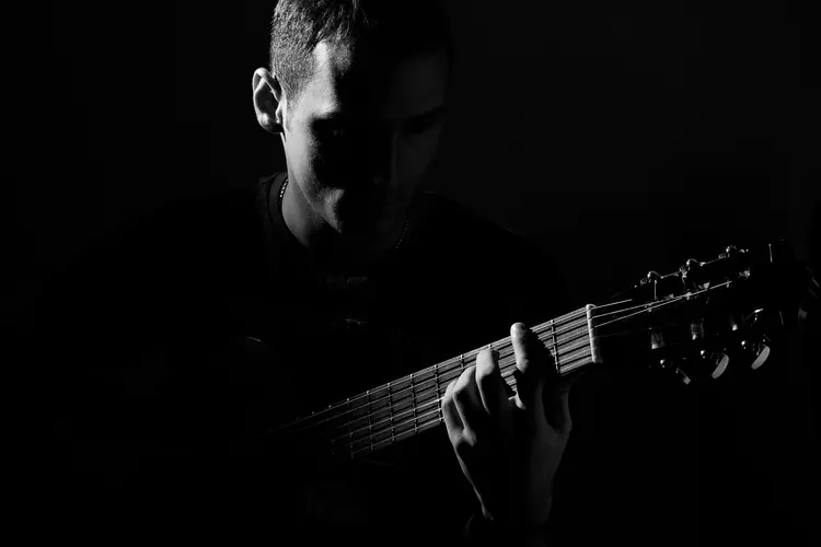 A black and white image of a man playing guitar.