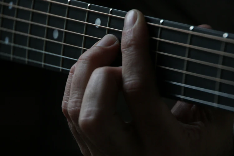 A person playing a chord on the guitar.