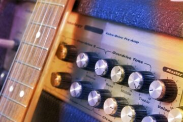 A close up image of an amp and the neck of a guitar.