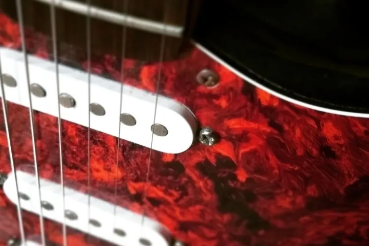 Stratocaster pickups on a red electric guitar.