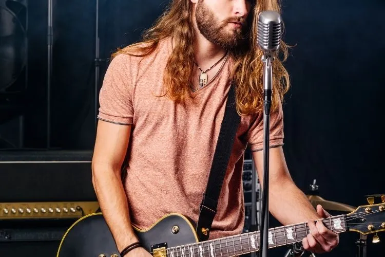 A musician with long hair, playing guitar.