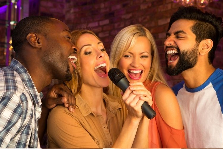 Two women and two men singing together at a karoake.