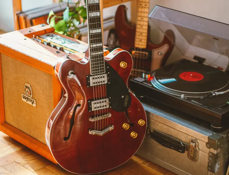 A 335 style guitar, Orange guitar amp, and record player.