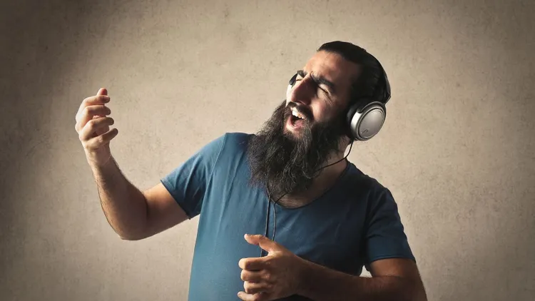 A man listening to music on his headphones and playing "air guitar"