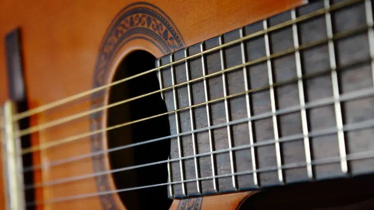 A close up of the guitar strings on an acoustic guitar.