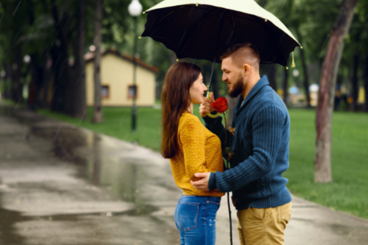 A couple standing yunder an umbrella in the pouring rain.
