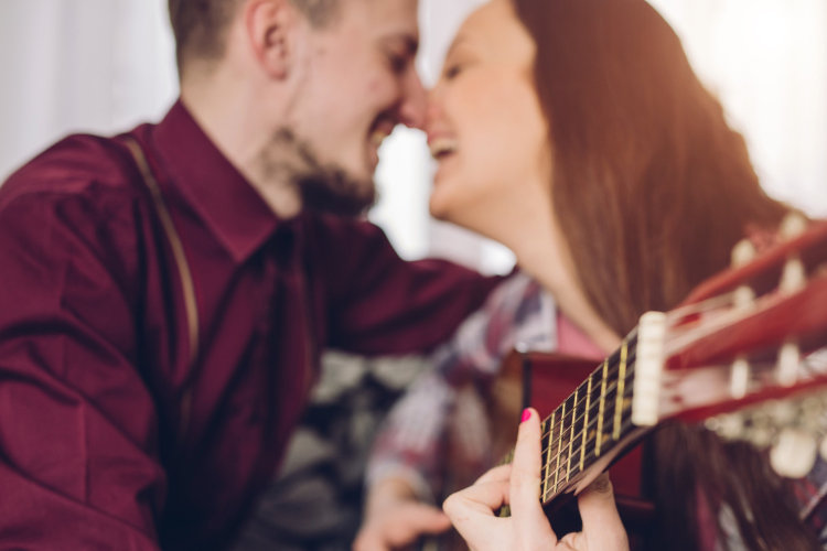 A couple enjoying some time together playing the guitar.
