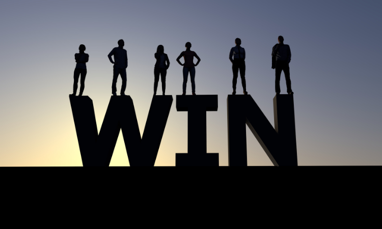Giant sized letter spelling out the word "win" with victorious people standing on top.